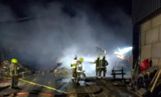Firefighters in front of a smouldering pile of rubbish