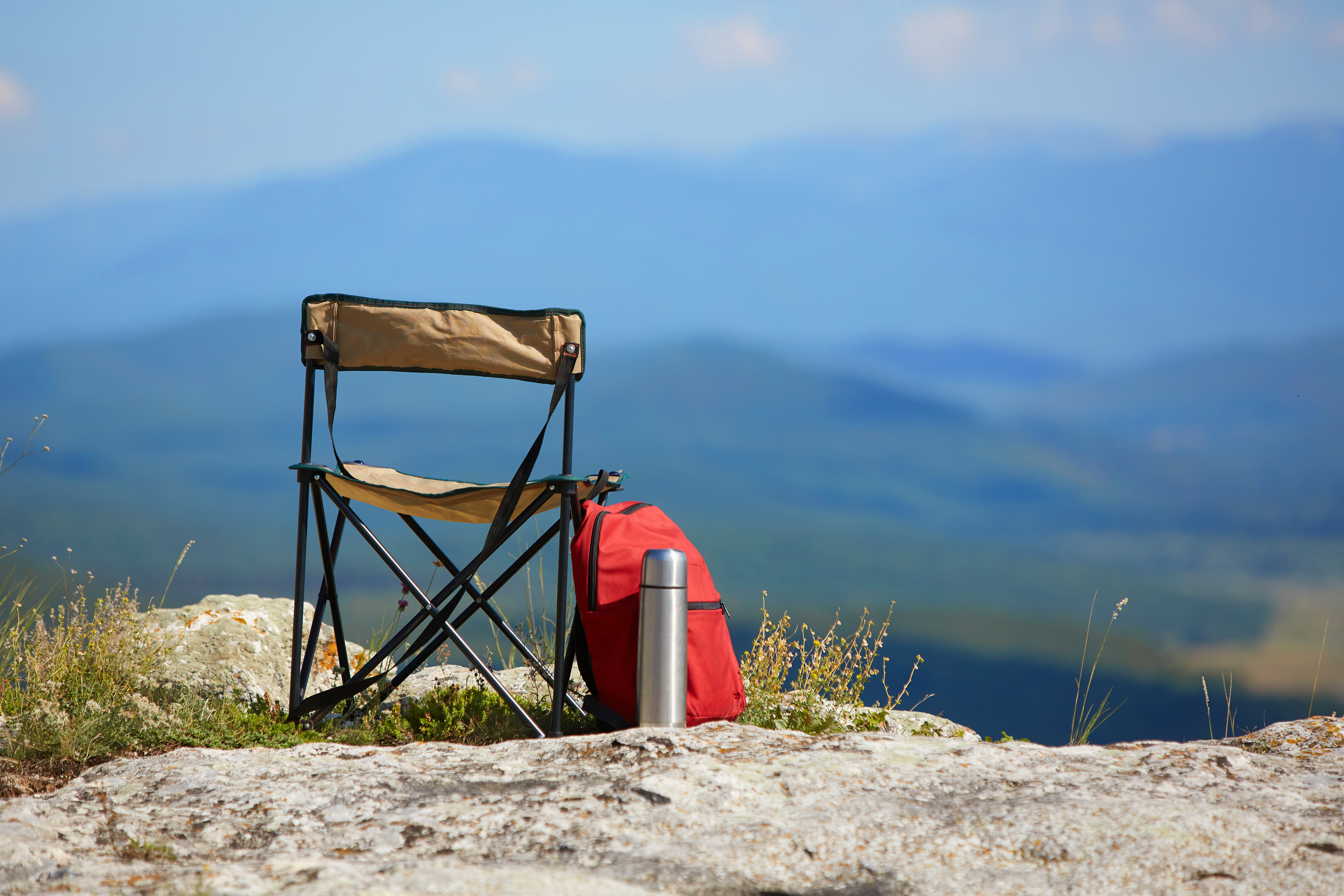 Camping chair on a hill with a backpack and a flask