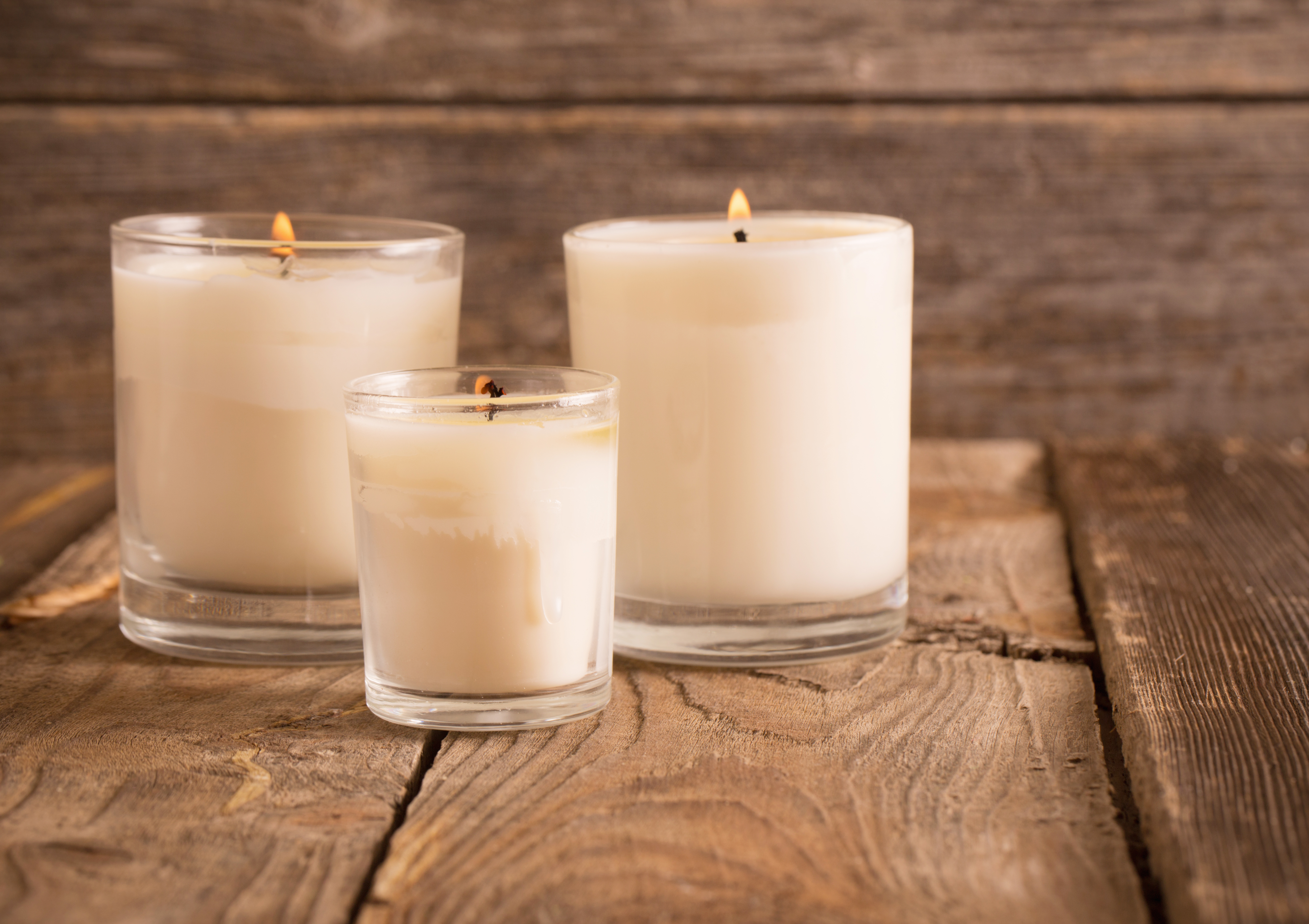 3 candles in glass holders on wooden table