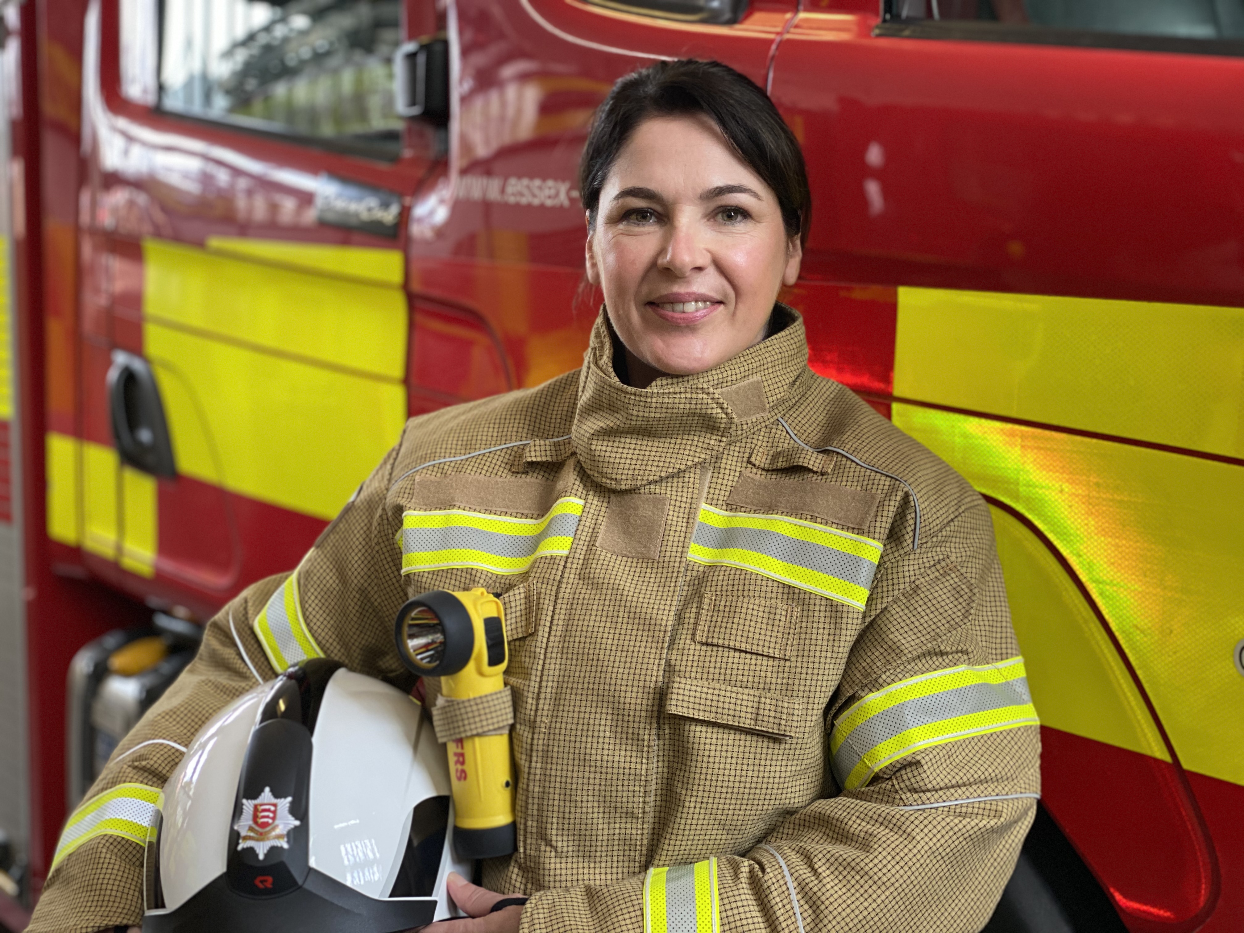 Our Deputy Chief Fire Officer Moira Bruin standing in front of a fire engine in her operational PPE. She is smiling.