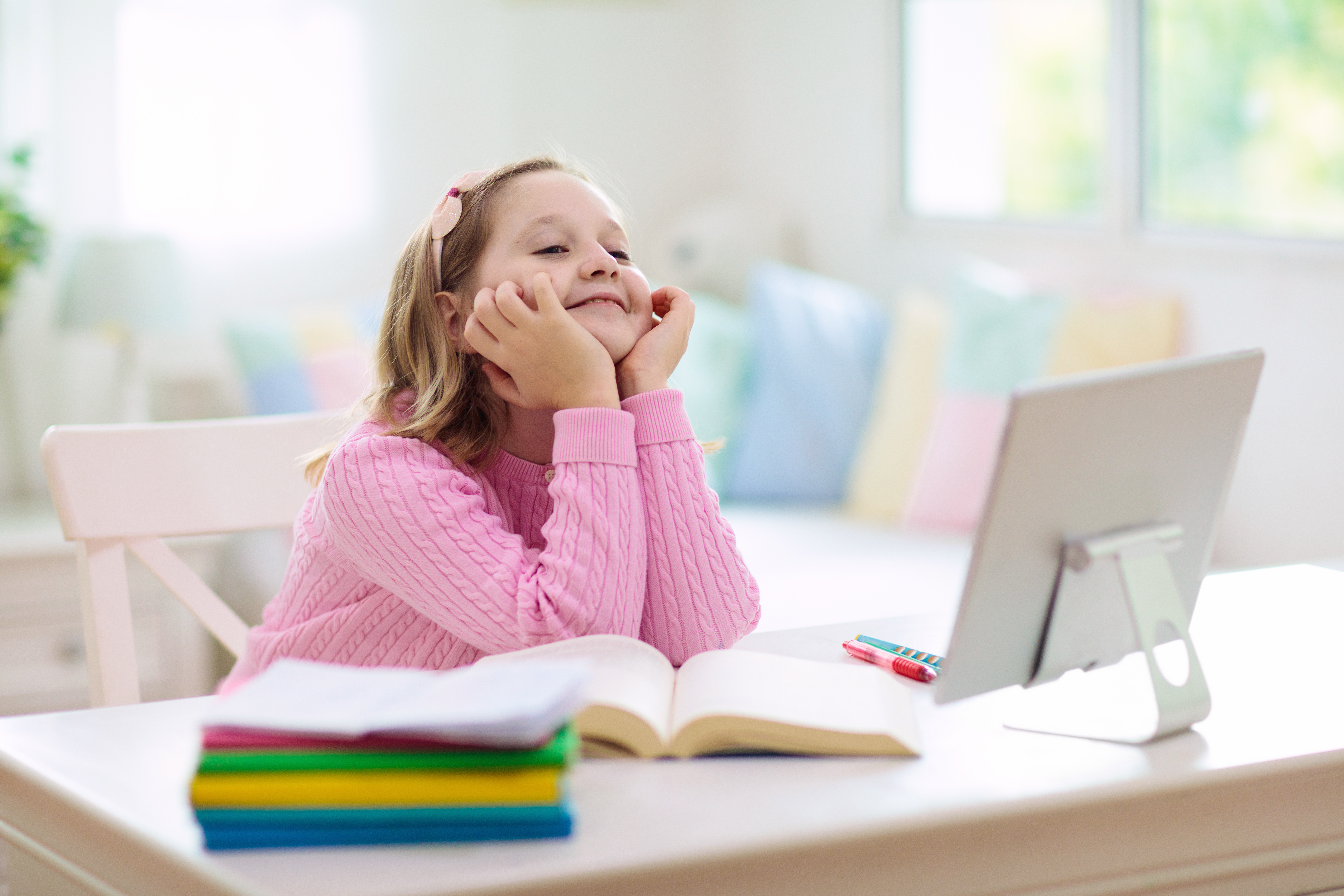 Girl, aged 9, wearing pink jumper sat at a laptop