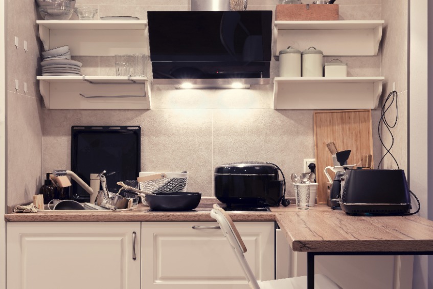 A kitchen with lots of mess on the work surfaces