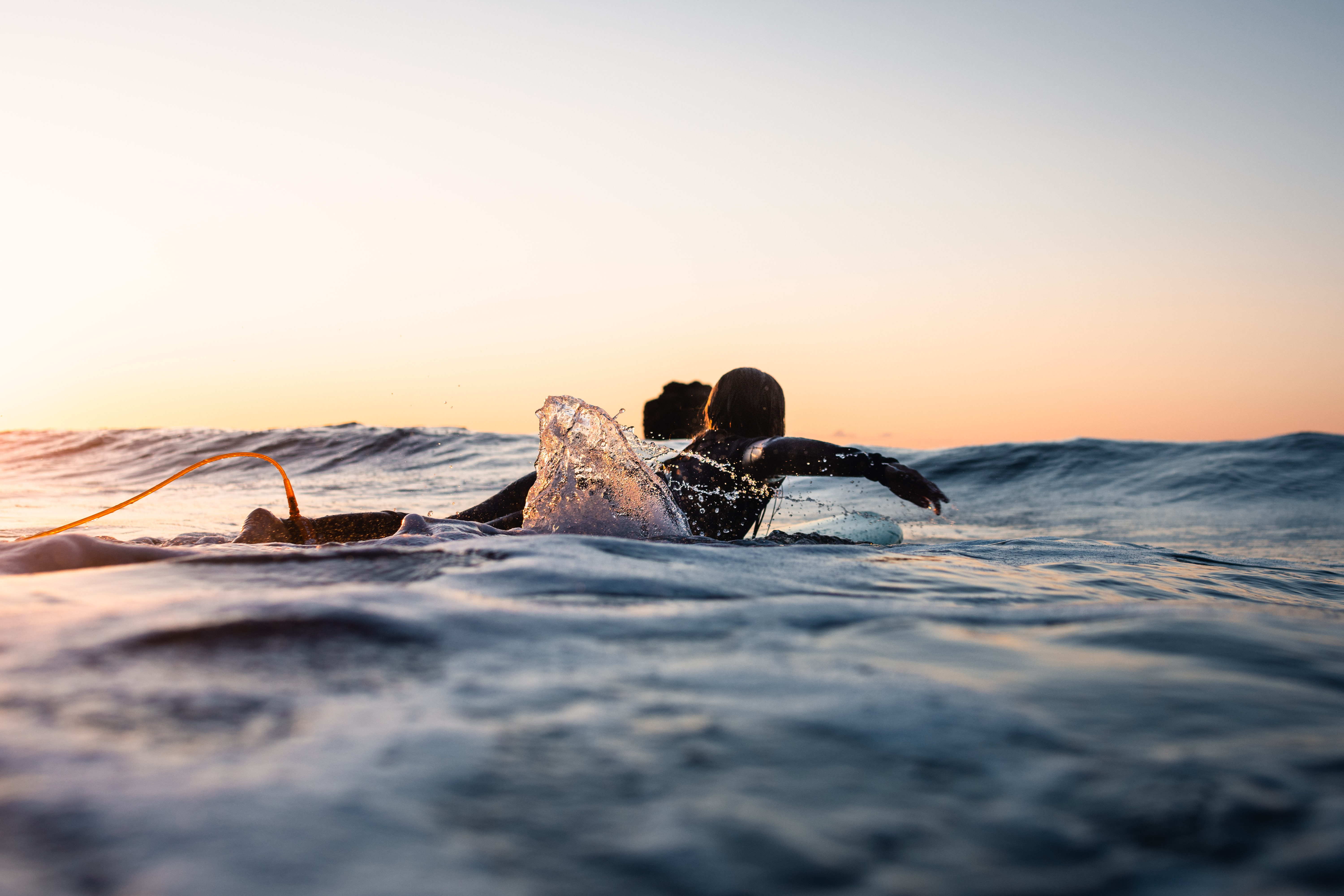 Surfer on surf board riding low waves as the sun comes up