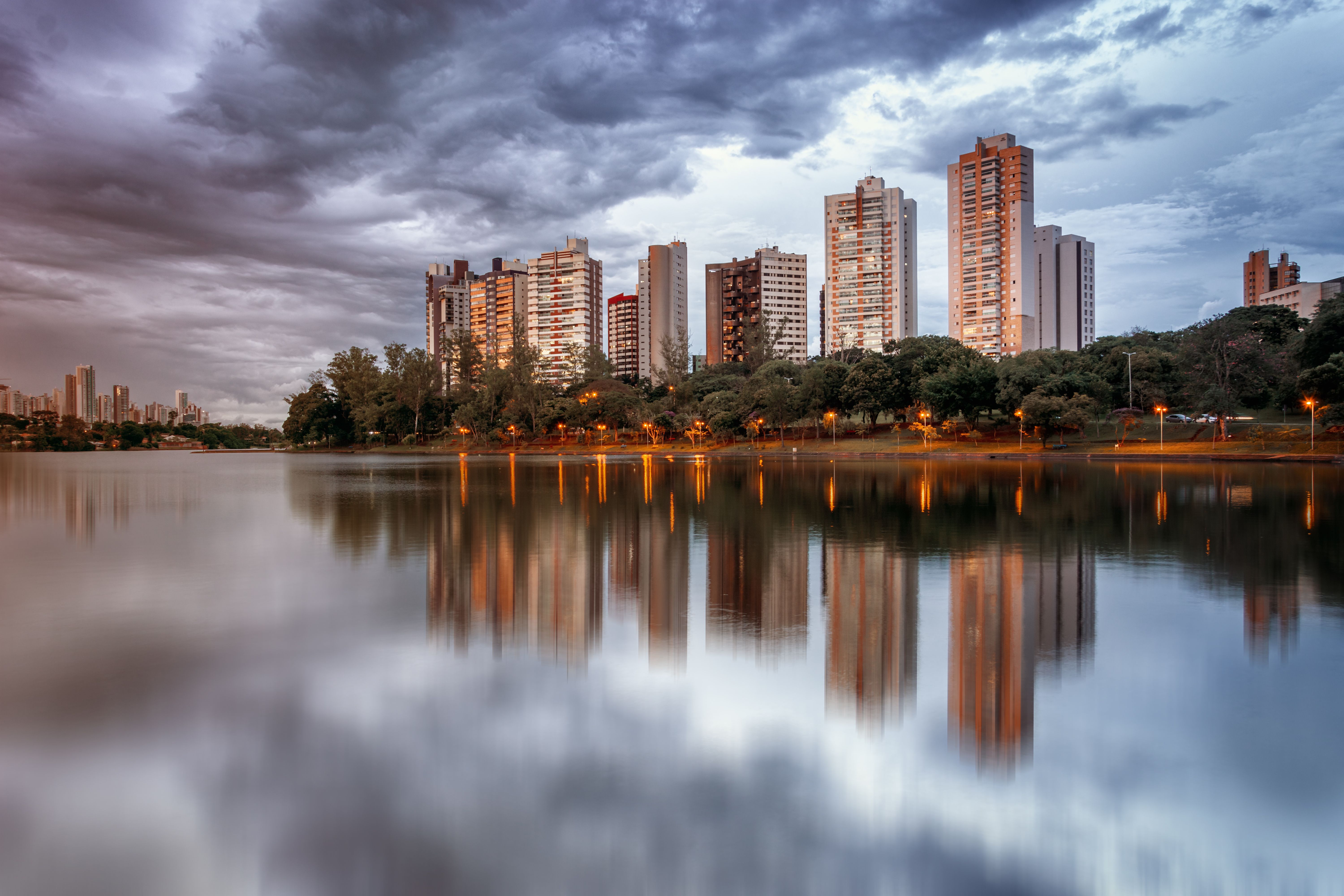 Several tall buildings sitting on the riverside at dusk