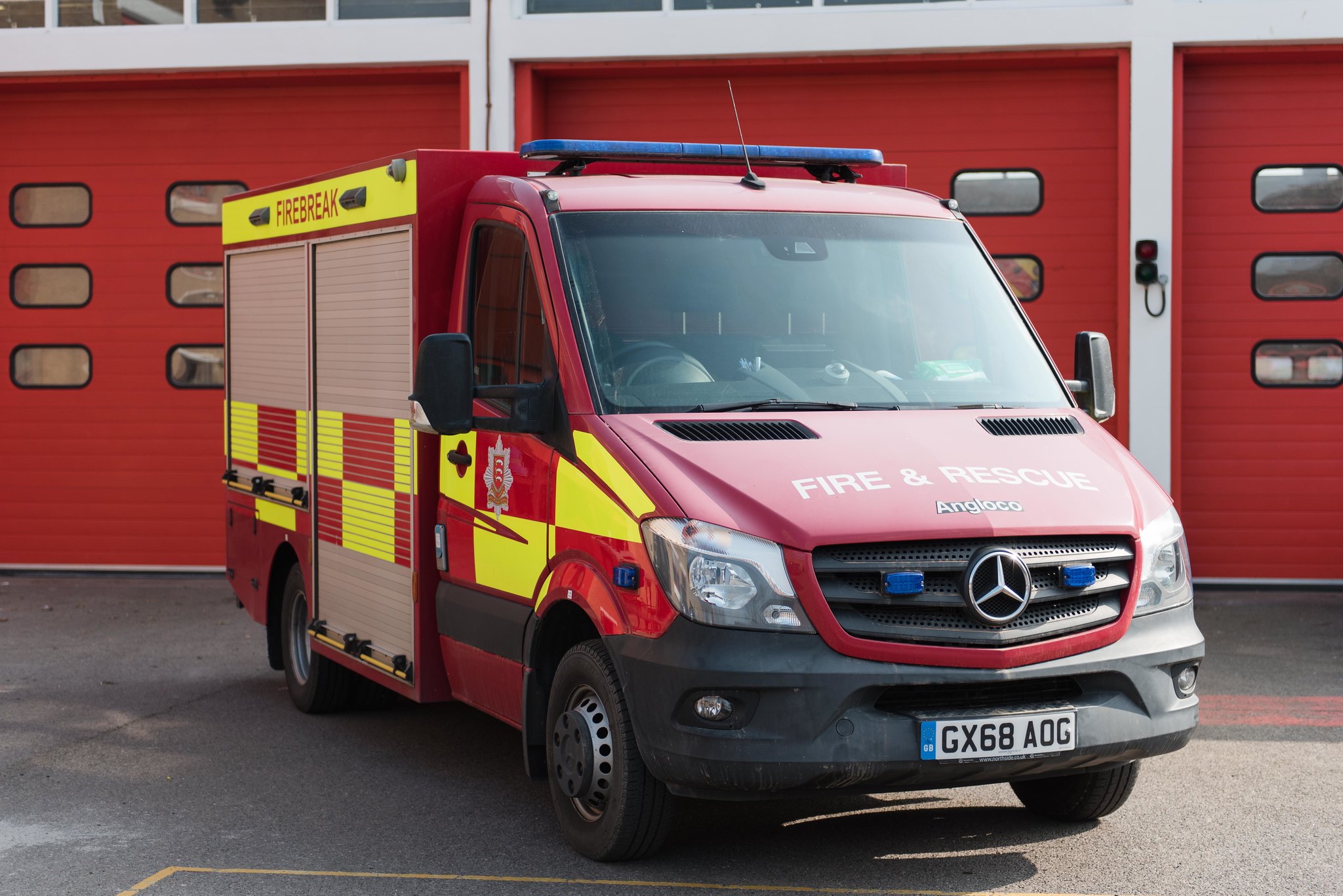 Fire & Rescue Van in front of 3 red bay doors