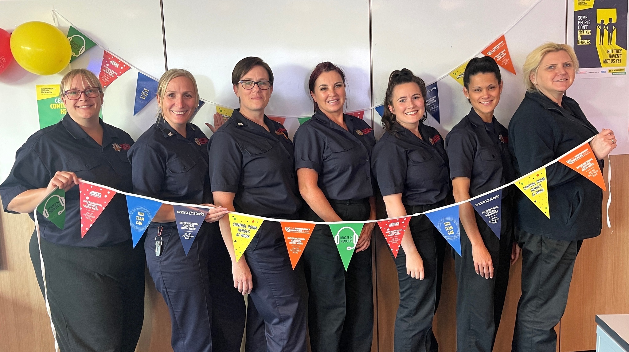 Green Watch Control team members Kristin, Vanessa, Gemma, Kelly, Johdi, Samantha and Rochelle holding multi-coloured bunting