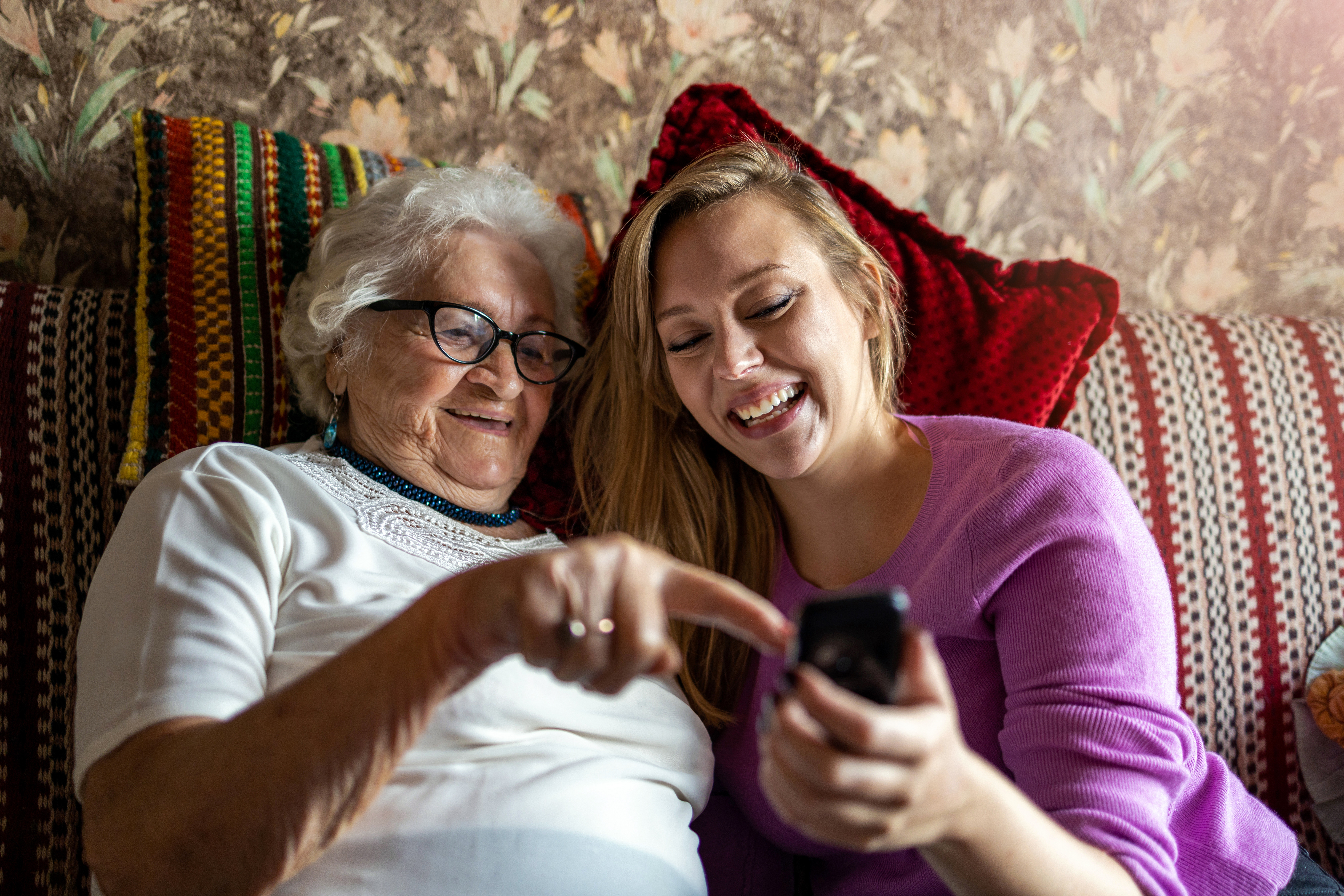 Young lady smiles at phone together with older lady