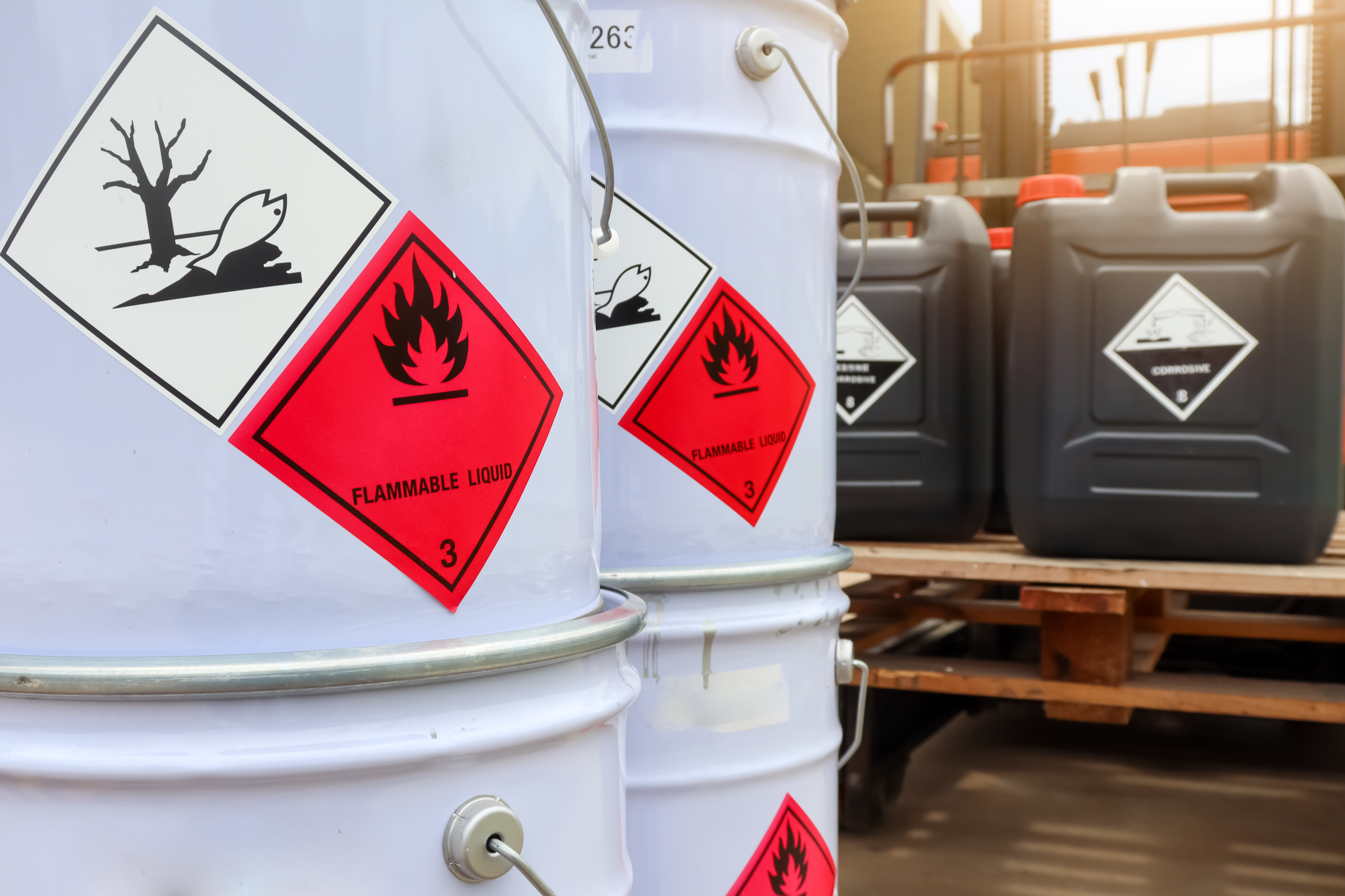 Two white containers and two smaller black containers with warning labels for corrosive substances