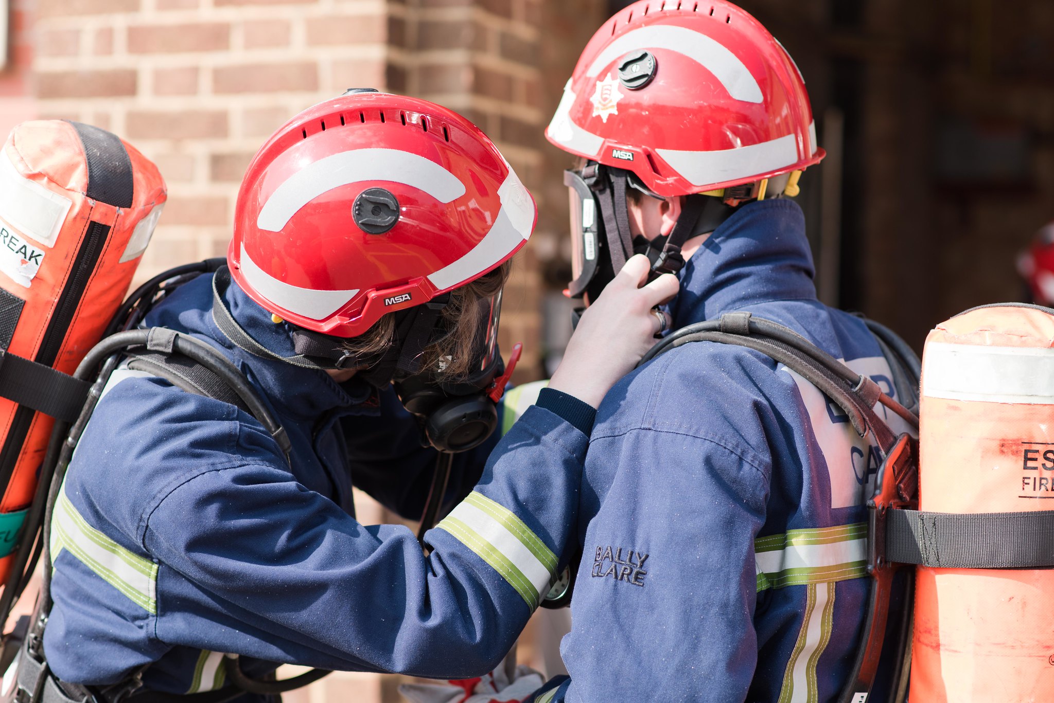 A fire cadet secures a helmet on a fellow fire cadet