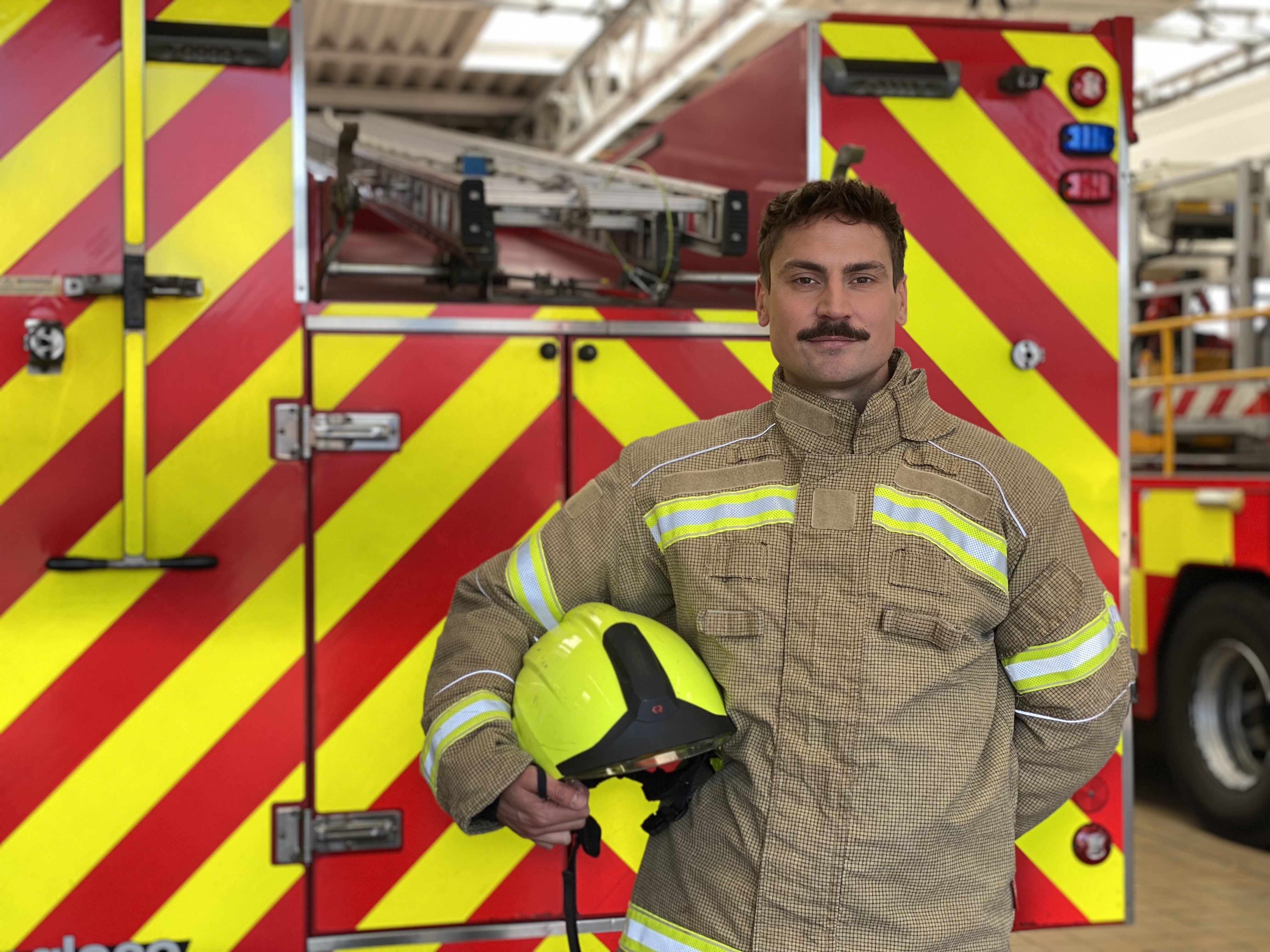 Firefighter Matt Hill standing in front of a fire engine
