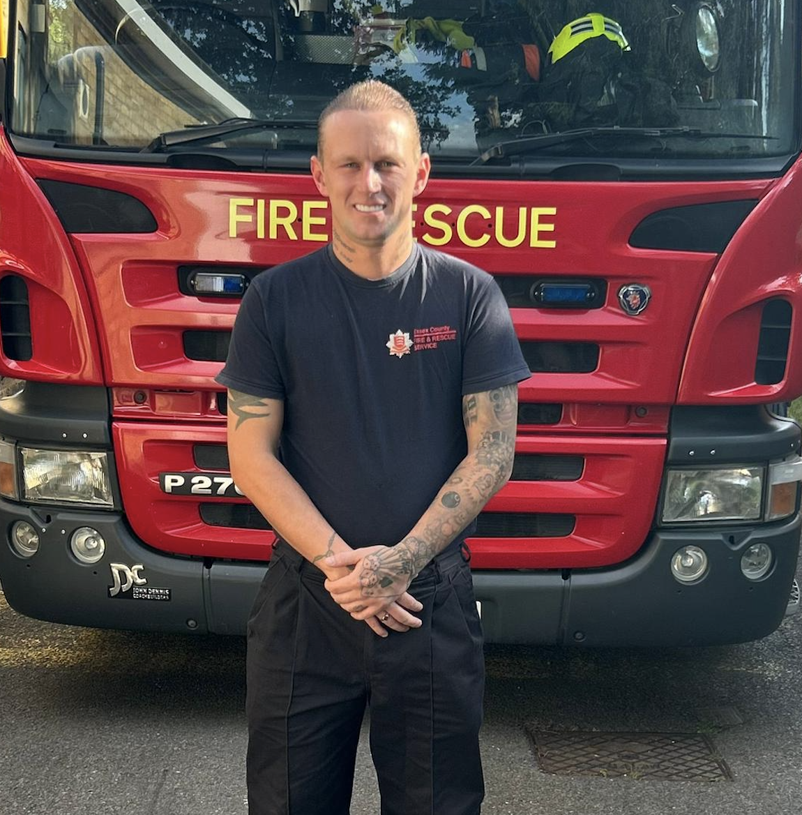 Firefighter Luke Oliver standing in front of a fire engine