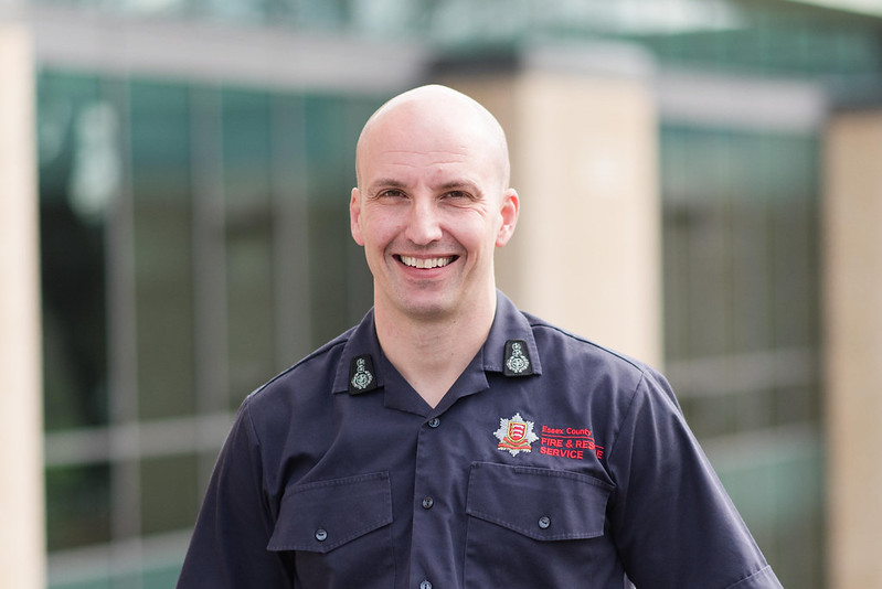 Chief Fire Officer Rick Hylton wearing a blue ECFRS shirt and standing in front of Fire HQ smiling at the camera