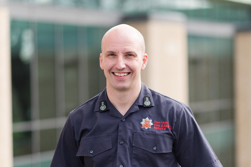 Chief Fire Officer Rick Hylton wearing a blue ECFRS shirt and standing in front of Fire HQ smiling at the camera