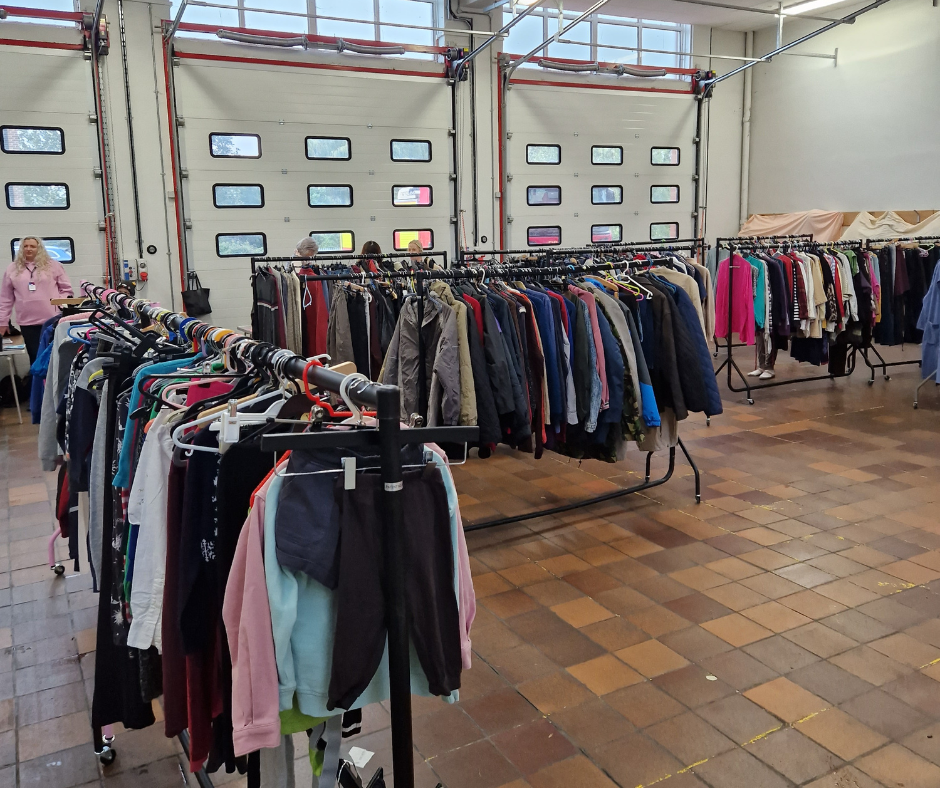 Clothes on racks at fire station being given away to people