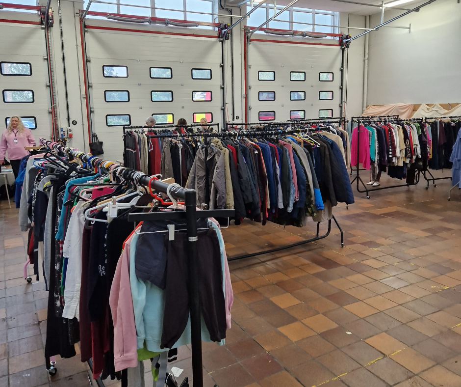 Clothes on racks at fire station being given away to people 