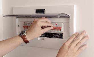 Women's hands resetting a fuse box on the wall