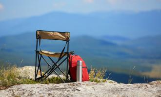 Camping chair on a hill with a backpack and a flask