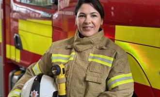 Our Deputy Chief Fire Officer Moira Bruin standing in front of a fire engine in her operational PPE. She is smiling.