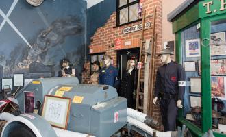 A pretend shop front from the 1930s with dummies dressed in unforms.