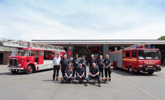 Two fire engines parked in front of the museum with two rows of volunteers lined up.