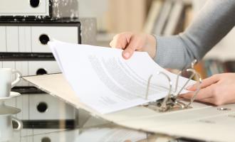 Two hands putting paper into a folder