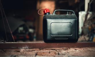 Black jerry can with red lid on garage floor