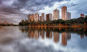 Several tall buildings sitting on the riverside at dusk