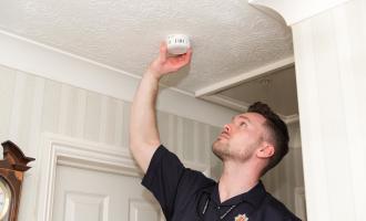 Community Safety Officer fits smoke alarm to the ceiling