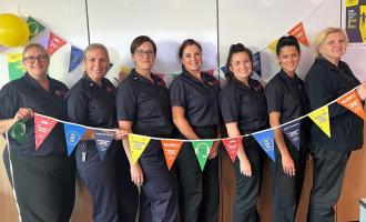 Green Watch Control team members Kristin, Vanessa, Gemma, Kelly, Johdi, Samantha and Rochelle holding multi-coloured bunting