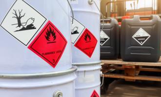 Two white containers and two smaller black containers with warning labels for corrosive substances