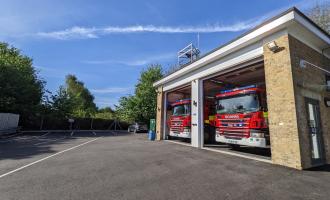 Two fire engines sat inside brick building with two open bay doors