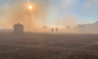 A smoke filed field with the image of a fire engine and firefighters just visible through the haze. 