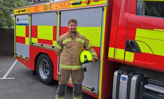 Firefighter Sam Hogwood in front of a fire engine