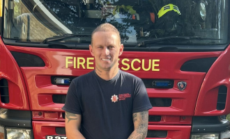 Firefighter Luke Oliver standing in front of a fire engine
