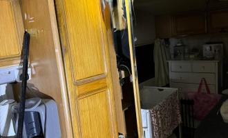 A fire damanged cupboard in a caravan with a cot next to it