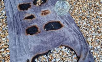 A crystal ball ornament on top of a blue towel, which has multiple burn marks