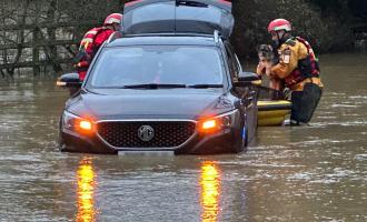 Crews rescuing a person and a dog from a car trapped in floodwater in Paper Mill Lock