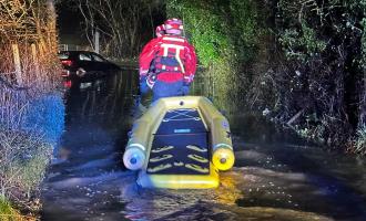 Specially trained water rescue firefighters rescuing a woman from a flooded road