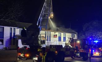 An Aerial Ladder Platform firing water on to the roof of a two storey building