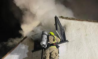 Firefighters on ladder extinguishing fire in roof