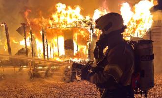 Firefighter standing in front of caravan on fire