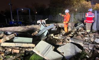 Pile of bricks following explosion with firefighters and a fire dog