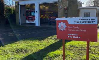 Stansted fire station in the background and a red sign with the name of the station in the foreground 