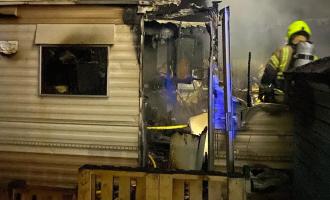A firefighter next to a burnt out caravan