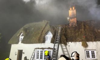 Crews extinguishing a thatch roof fire