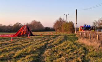 A hot air balloon in a field next to a fire engine