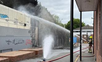 A firefighter spraying water on a smouldering building