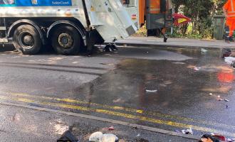 A burnt out e-scooter in front of a refuse lorry