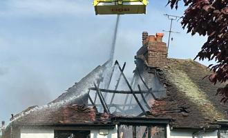 A firefighter in an Aerial Ladder Platform spraying water on the roof