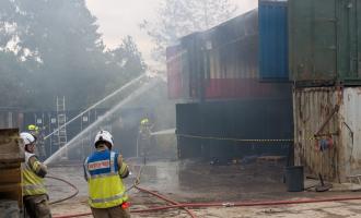 Firefighters spraying water on the containers